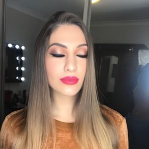 Close-up of woman with soft glam makeup, neutral eyeshadow, and bold pink lips.