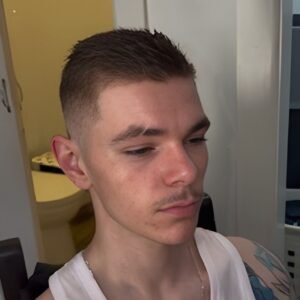 Men's fade haircut with textured top and clean sides.